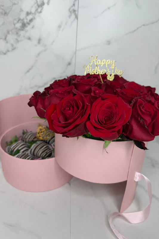 Bouquet of red roses in a pink box with 'Happy Mother's Day' candle on a marble background